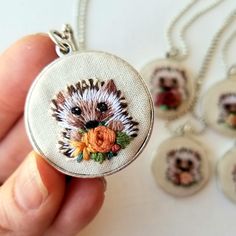 a hand holding a small pendant with an image of a dog and flowers on it