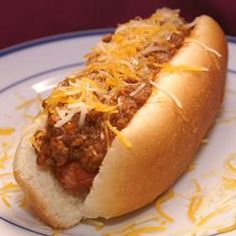 a chili dog on a plate with cheese