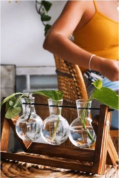 three vases with plants in them sitting on a wooden tray next to a wicker chair