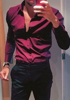 a man is taking a selfie in the mirror with his cell phone while wearing black pants and a pink shirt