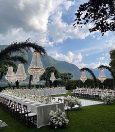 an outdoor wedding setup with chandeliers and tables set up for the guests to eat