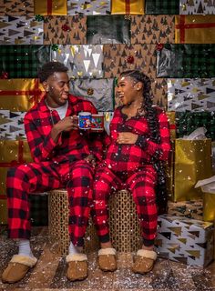 two people dressed in red and black pajamas sitting next to each other on christmas presents