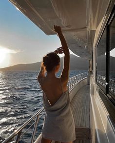 a woman in a towel standing on the deck of a boat looking out at the ocean