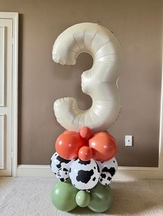 the balloon is shaped like a number and has balloons attached to it with cow print on them