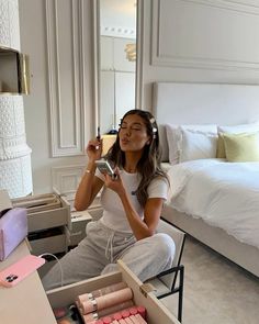 a woman sitting on a bed holding a cell phone