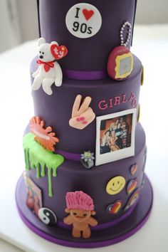 a three tiered purple cake decorated with pictures and other things on it's side