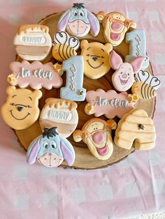 winnie the pooh cookies are arranged on a wooden platter with pink and white checkered tablecloth