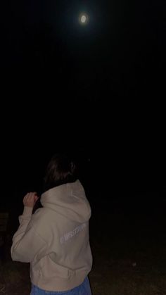 a person standing in the grass at night with a frisbee flying through the air