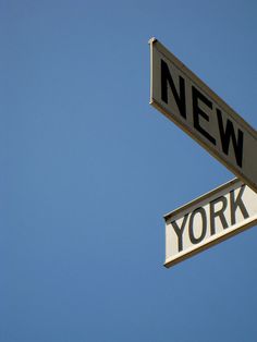 two street signs on top of each other in front of a blue sky with no clouds