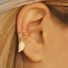 a close up of a person's ear with a leaf charm on the end