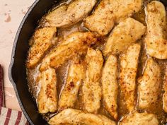 chicken is cooking in a skillet with brown sauce on the side and a striped napkin next to it