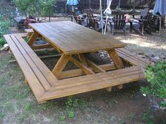 a wooden picnic table sitting in the middle of a yard