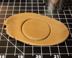 a piece of wood sitting on top of a cutting board next to a ruler and cup