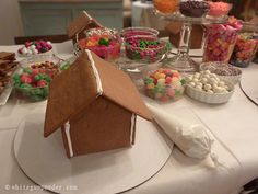 a gingerbread house on a table with candy and candies in bowls around it