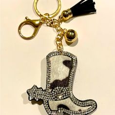 a keychain with a cowboy boot and black tassel on it's side