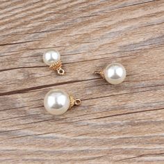 three pairs of pearl earrings sitting on top of a wooden table