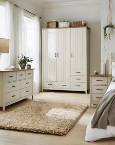 a bedroom scene with focus on the bed, dresser and armoires that are all white