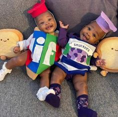 two babies sitting next to each other holding stuffed animals