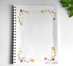 an open notebook with flowers on it next to a plant