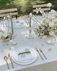 the table is set with white flowers and gold cutlery for an elegant wedding reception