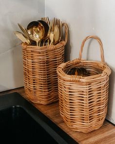 two wicker baskets filled with golden spoons and utensils on a counter