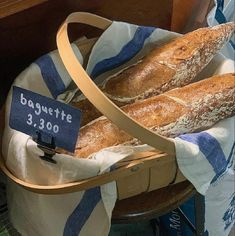 two loaves of bread sitting in a basket on top of a table next to a baguette sign