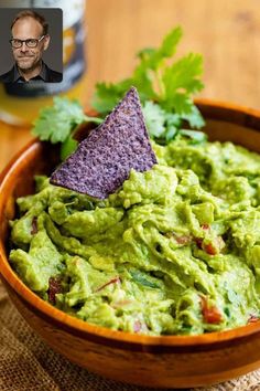 a wooden bowl filled with guacamole and a purple tortilla chip