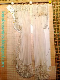 two white sheer curtains hanging on a wall next to a piece of wood and wire