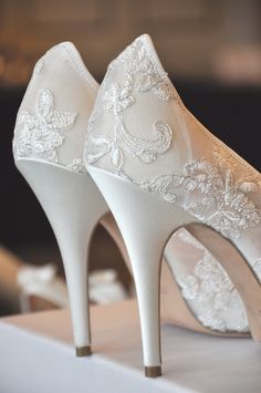 a pair of white wedding shoes sitting on top of a table