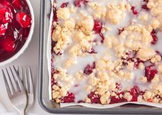 a pan filled with cranberry cobbler next to a bowl of cherries