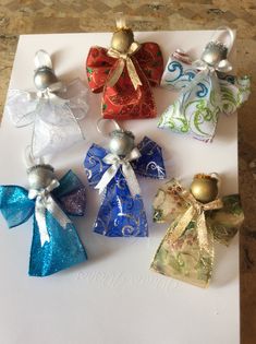 six small christmas bells on top of a piece of paper with ribbons and bows around them