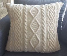 a white knitted pillow sitting on top of a blue couch