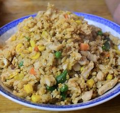 a blue and white bowl filled with rice and veggies on top of a wooden table