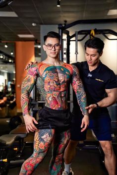 a man with tattoos and leggings standing next to another man in a gym