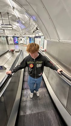 a young boy is standing on an escalator at the airport with his arms outstretched