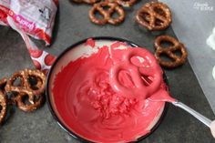 a person is dipping some kind of candy into pretzels with red icing