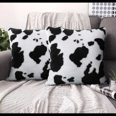 two black and white cow print pillows on a couch