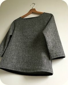 a gray sweater hanging on a white wall