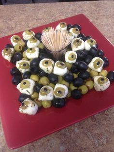 an arrangement of olives and mushrooms on a red platter with toothpicks