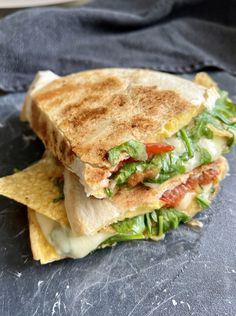 a sandwich with lettuce, tomato and cheese on it sitting on a slate board