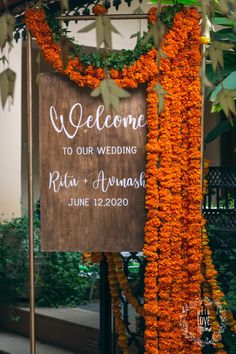 a welcome sign is adorned with orange flowers