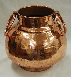 a large metal vase sitting on top of a white table