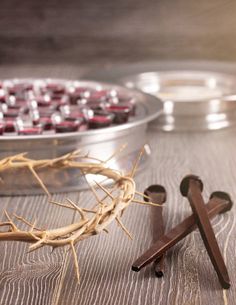 a crown of jesus and two crosses on a wooden table next to a tray with candles