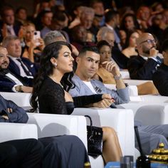 several people sitting in white chairs watching something