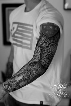 black and white photograph of a man's arm with an intricate tattoo design on it