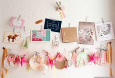 there are many pictures and cards hanging on the wall with ribbons attached to each one