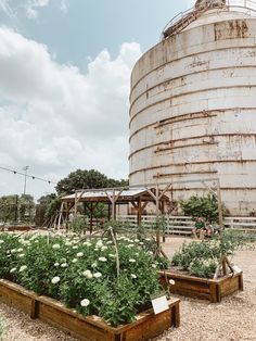 an old grain silo sits in the middle of a field with many plants and flowers