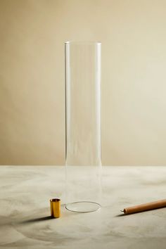 a glass vase with a pencil next to it