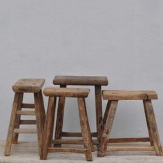 three wooden stools sitting next to each other in front of a white wall,