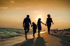 a family standing on the beach at sunset